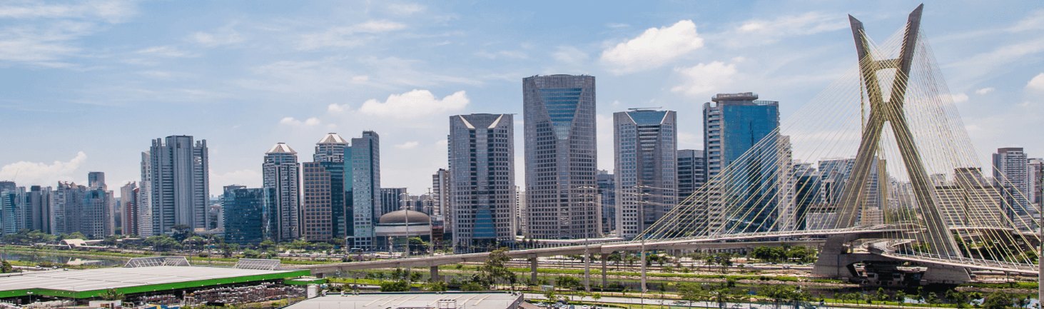 Urban skyline featuring the Estaiada Bridge and modern skyscrapers in São Paulo, Brazil, under a blue sky with clouds.