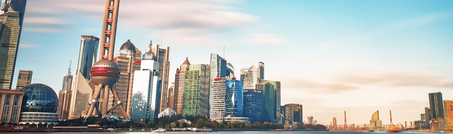 Panoramic view of the Shanghai Bund, showcasing a vibrant skyline with a mix of historic colonial buildings along the waterfront and modern skyscrapers in the background, under a clear sky.